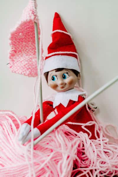 knitting with pink wool. Elf on the shelf
