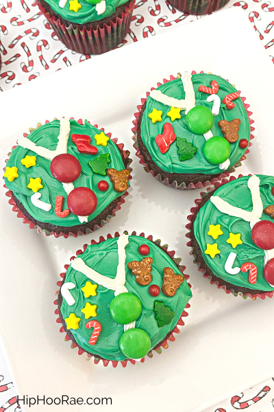 4 Cupcakes decorated like an Ugly Christmas Sweater on a white plate