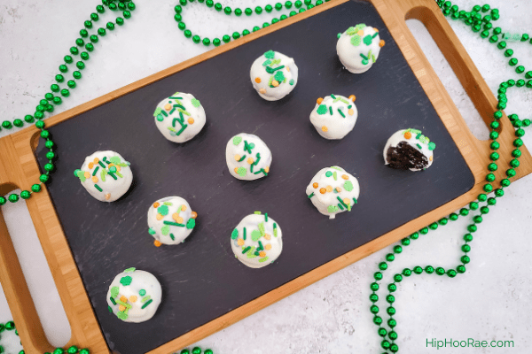 Tray with 11 St Patrick's Day oreo truffles on it with green bead necklace on table as a display