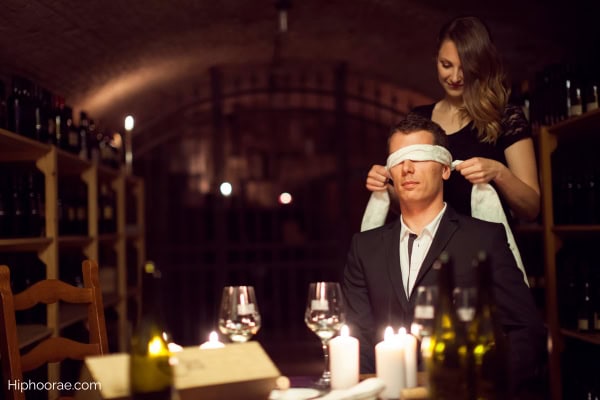 Woman putting a blindfold on her boyfriend over dinner