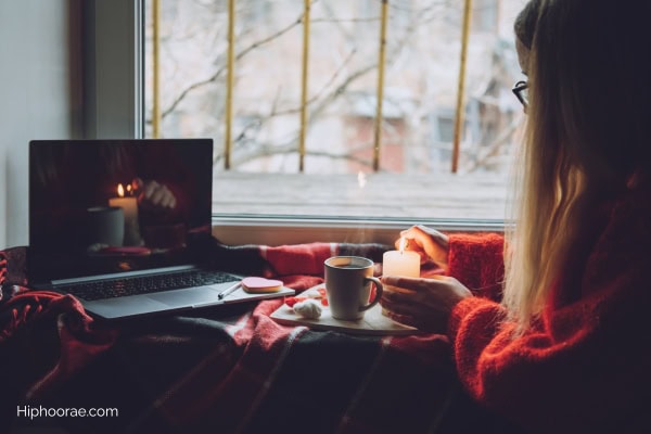 Woman in front of laptop , lighting a candle