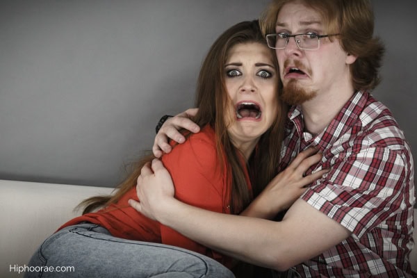 couple looking scared while watching horror movie