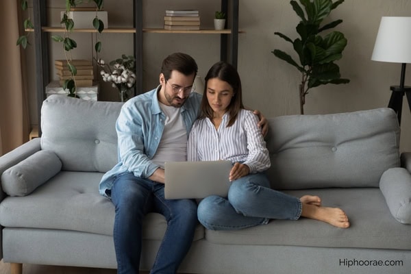 couple sitting on couch looking at laptop