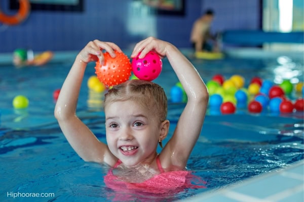 little girl playing with balls in pool