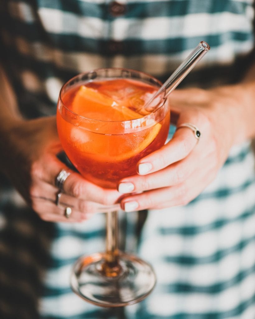 lady holding a glass of aperol spritz cocktail