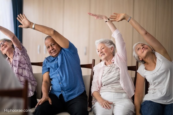 group of seniors stretching while sitting on chairs