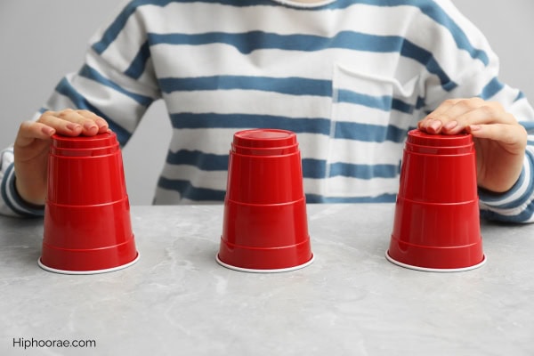 person playing cup shuffle