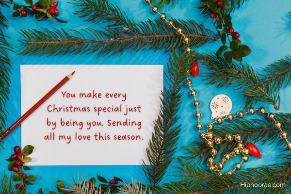 Christmas decorations of green branches, white card with Christmas message written on it