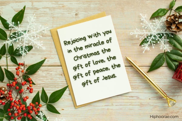 Christmas decorations on wooden table, white card with Christmas message written on it