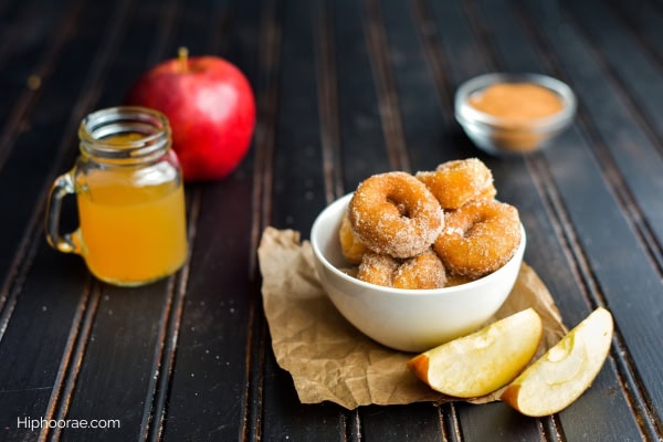 glass of cider, bowl of donuts, apples on table