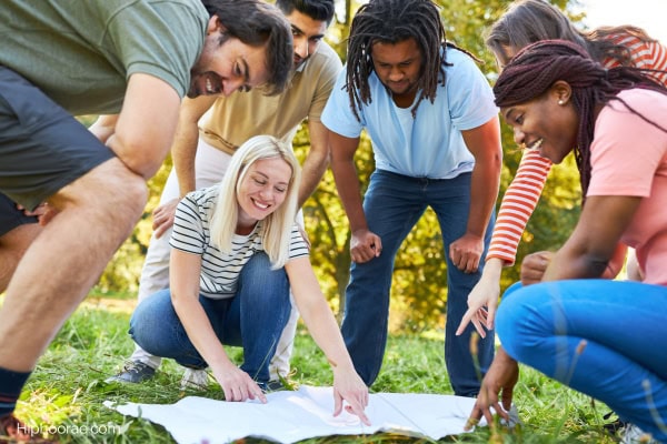 group of young men and women looking at a map outdoors for a scavenger hunt