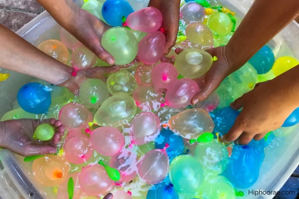 hands grabbing water balloons from a bucket