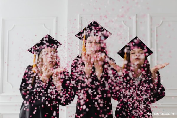 young graduates blowing confetti