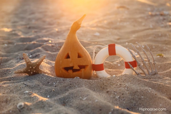carved pumpkin, lifebuoy, starfish, skeleton hand on beach