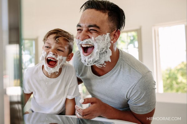 Father and son with shaving cream on their faces laughing
