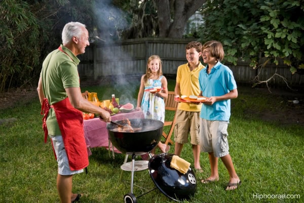 Father grilling burgers in backyard, kids waiting
