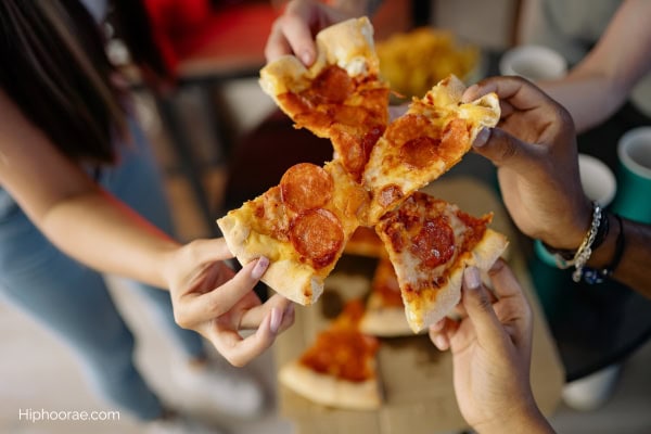 people holding pizza slices to toast