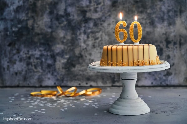 gold birthday cake with the number 60 candles with black background
