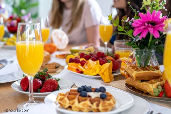 brunch party food spread of waffles, fruits, orange juice, and other breakfast foods
