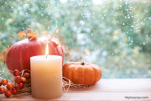 lighted candle with fall decorations by the window ledge
